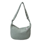 Sac à bandoulière vert en tissu côtelé avec breloque, design moderne et minimaliste, idéal pour un style décontracté et tendance.