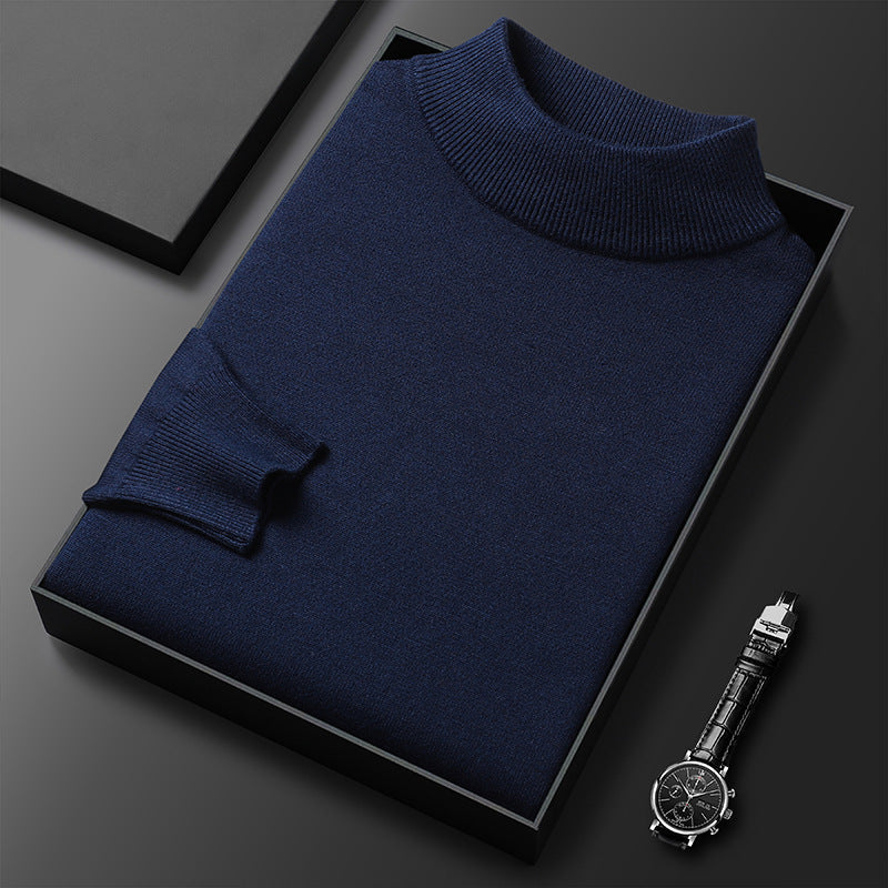 Pull-over bleu marine en laine, col roulé, présenté dans une boîte noire élégante, accompagné d'une montre-bracelet noire sur fond sombre.