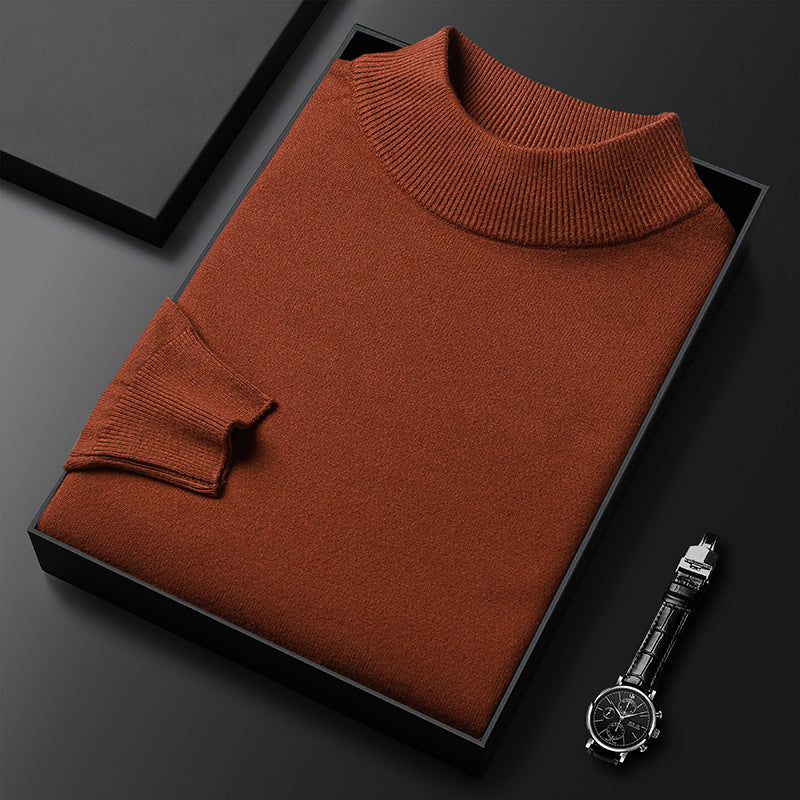 Pull-over col roulé marron en laine, soigneusement plié dans une boîte noire, accompagné d'une montre-bracelet élégante sur fond noir.