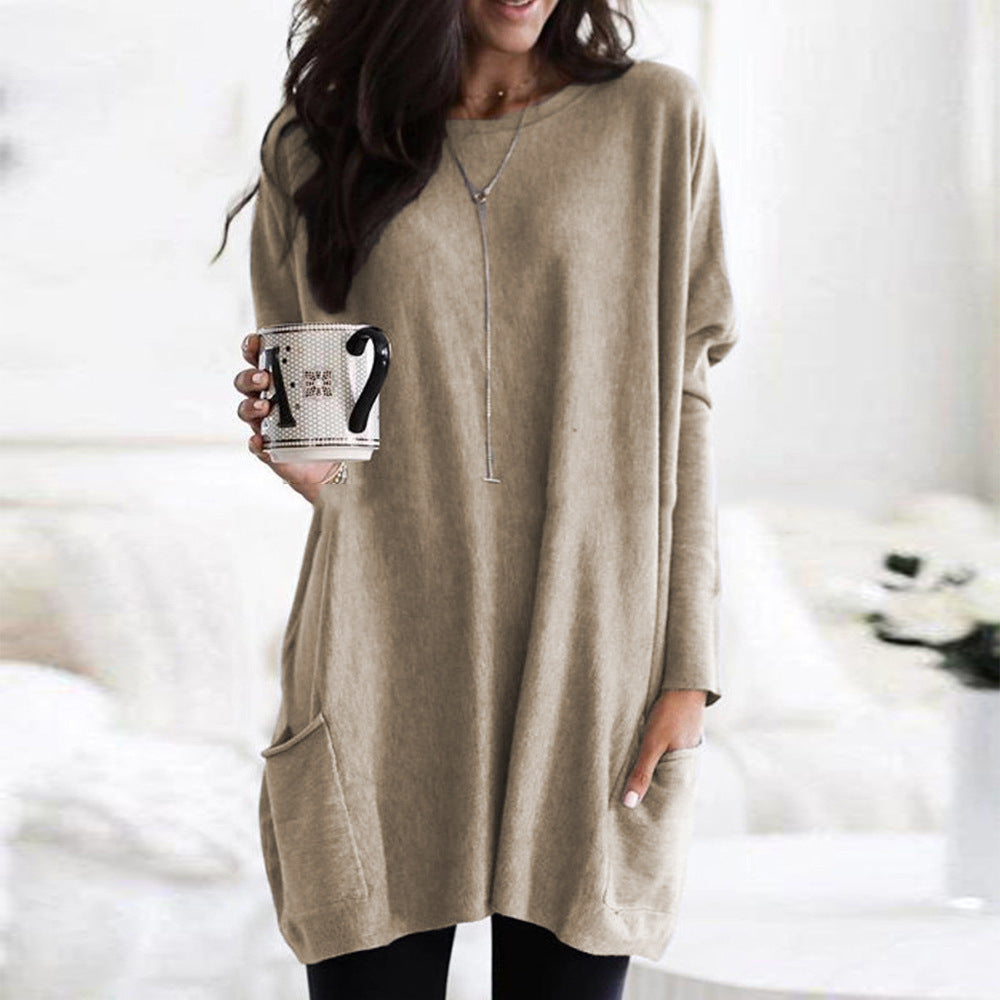Femme portant un pull beige ample, tenant une tasse de café noir et blanc, dans un intérieur lumineux. Mode décontractée, style automne-hiver.