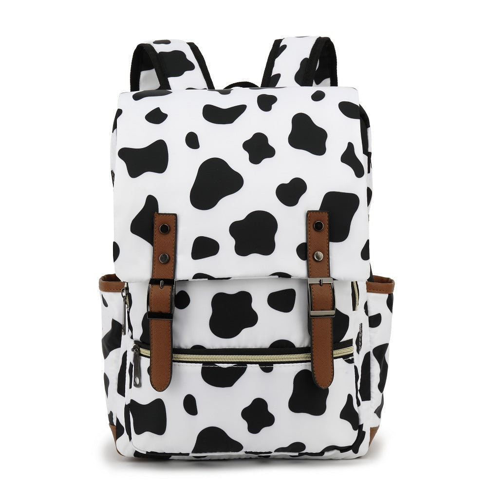 Sac à dos motif vache noir et blanc, design moderne, poches latérales, fermetures éclair, bretelles ajustables, idéal pour école ou voyage.