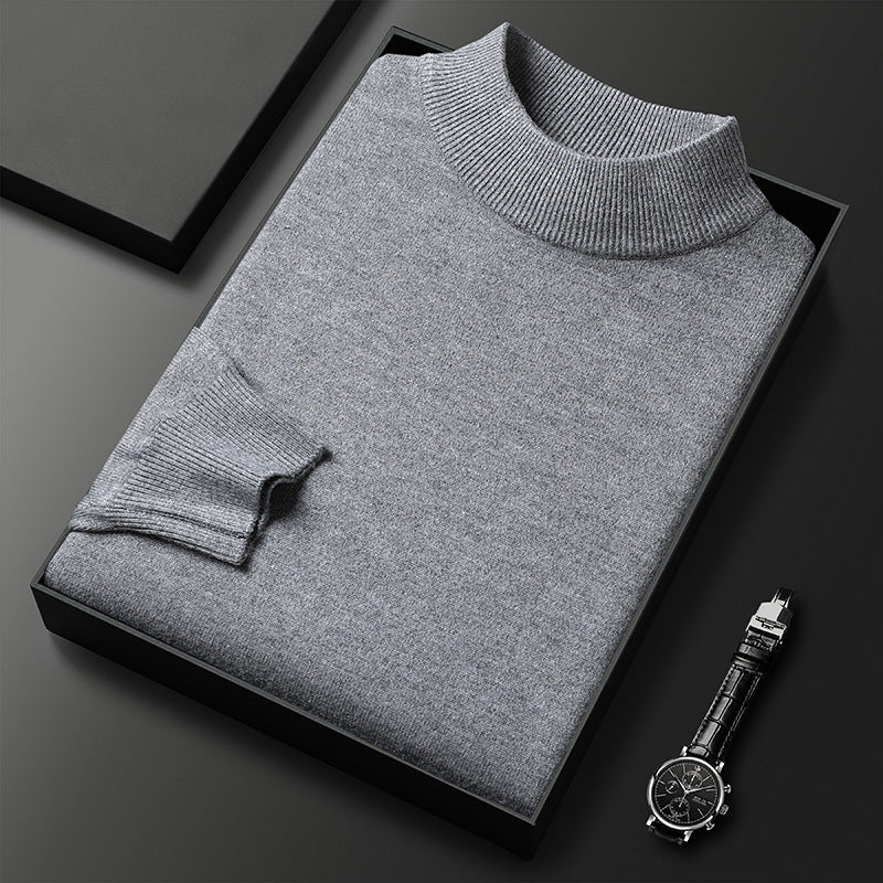 Pull-over gris en laine plié dans une boîte noire, accompagné d'une montre-bracelet élégante sur fond noir. Mode masculine, vêtements d'hiver.