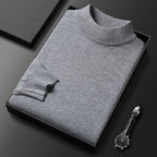 Pull-over gris en laine plié dans une boîte noire, accompagné d'une montre-bracelet élégante sur fond noir. Mode masculine, vêtements d'hiver.