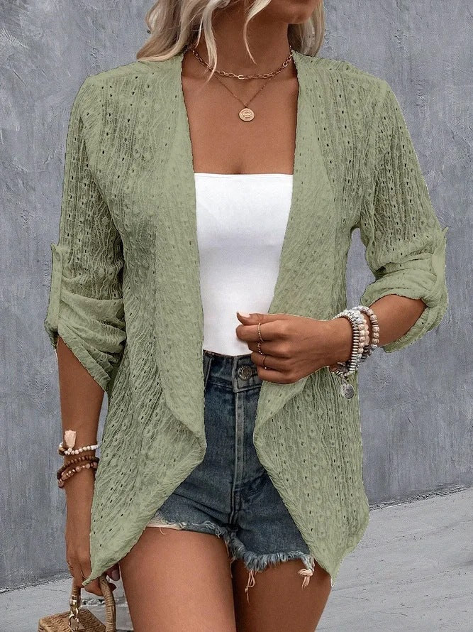 Femme en gilet vert en dentelle, top blanc, short en jean, accessoires bohèmes; mode estivale décontractée, tendance et élégante.
