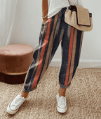 Pantalon à rayures multicolores, style décontracté, porté avec un sac en paille et des baskets blanches, mode féminine tendance.