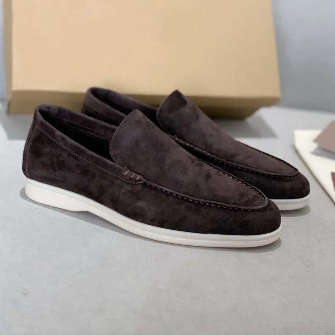 Mocassins en daim marron foncé pour homme avec semelle blanche, posés sur une surface grise, boîte en arrière-plan. Chaussures élégantes et confortables.