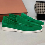 Paire de mocassins en daim vert vif avec semelle blanche, posée sur une surface grise. Chaussures élégantes pour homme, style moderne et tendance.