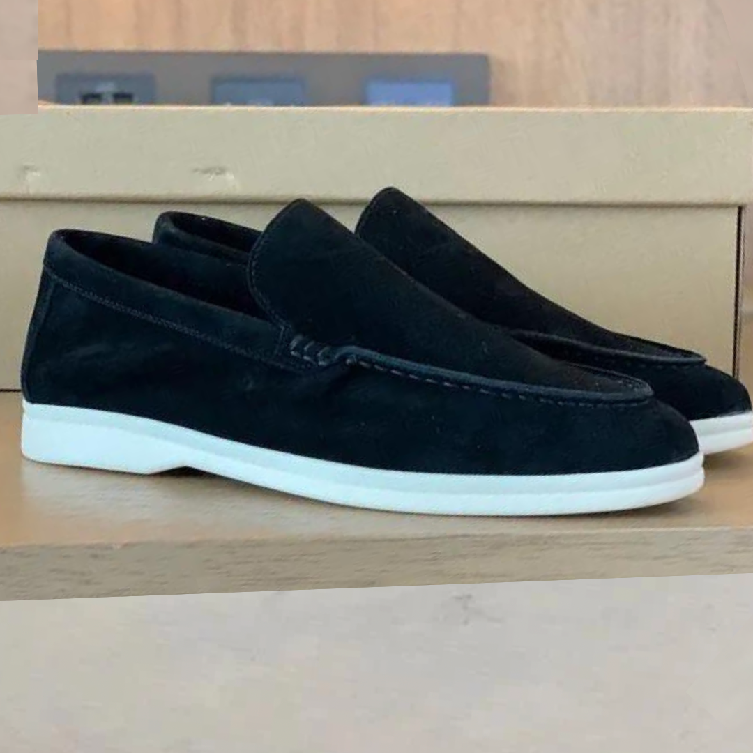 Chaussures mocassins en daim noir pour homme, semelle blanche, posées sur une boîte en carton. Style élégant et décontracté, parfait pour la mode masculine.