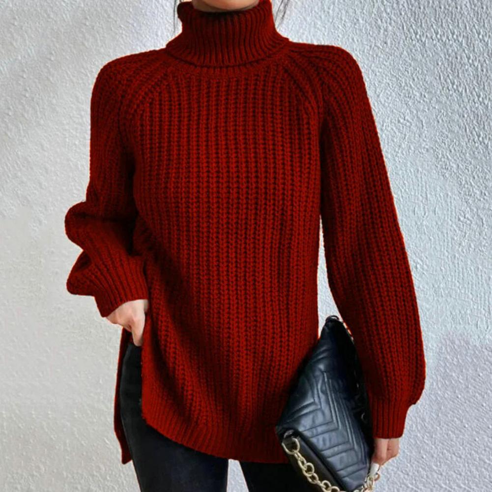 Femme portant un pull rouge à col roulé en tricot, tenant un sac à main noir matelassé avec chaîne dorée. Mode automne-hiver, style élégant.