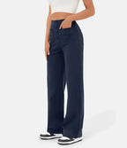 Femme portant un pantalon large bleu marine taille haute avec poches, associé à un haut blanc court et des baskets noires et blanches.