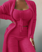 Femme portant un ensemble rose en tricot texturé, composé d'un cardigan, d'un haut court et d'un pantalon. Mode féminine, tenue confortable.