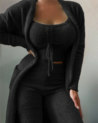 Femme portant un ensemble noir en tricot, composé d'un cardigan, d'un haut court et d'un pantalon taille haute. Mode automne-hiver élégante et confortable.