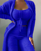 Femme portant un ensemble en tricot bleu vif, composé d'un cardigan, d'un haut court et d'un pantalon taille haute. Mode tendance et confortable.