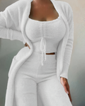 Femme portant un ensemble loungewear blanc en tricot, composé d'un cardigan, d'un top court et d'un pantalon. Mode confortable et élégante.