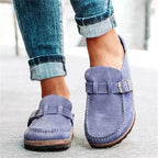 Chaussures mocassins en daim bleu pour femme, avec boucle décorative, portées avec un jean retroussé. Mode féminine, style décontracté, tendance.