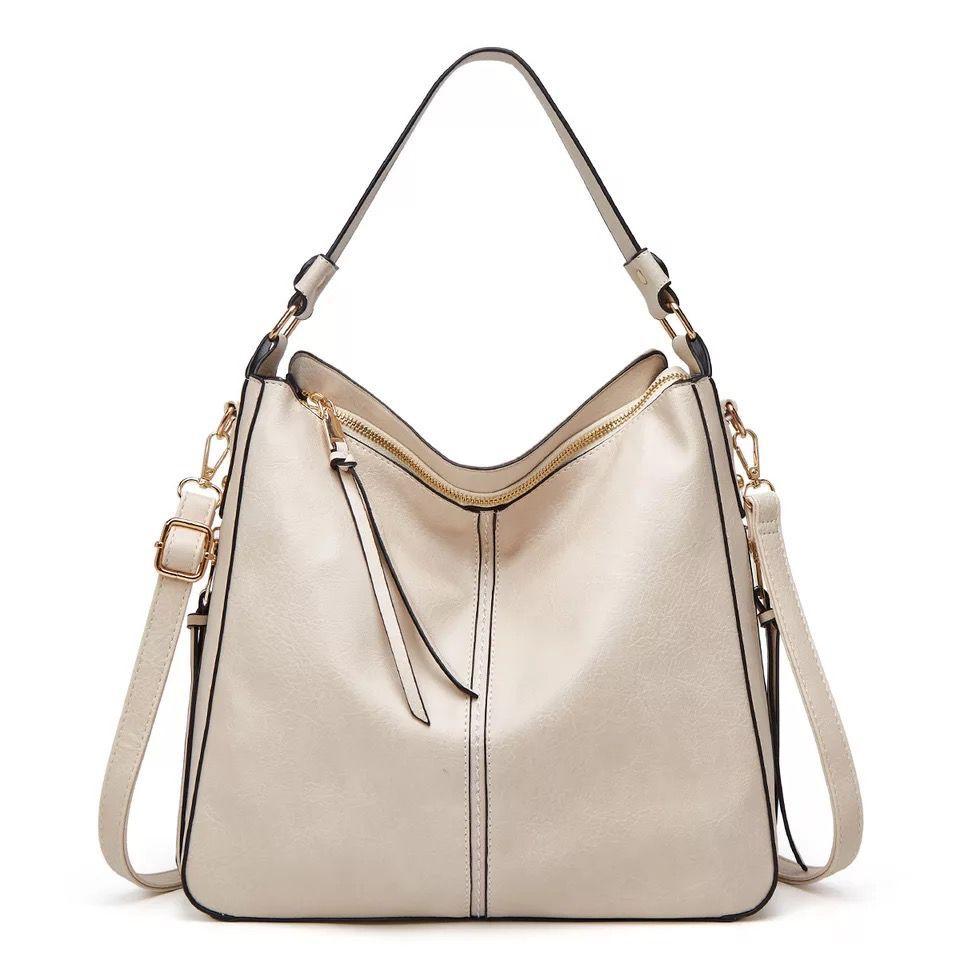 Sac à main en cuir beige élégant avec bandoulière réglable, fermetures éclair dorées et détails noirs. Accessoire mode femme chic et tendance.