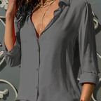 Chemisier gris élégant pour femme, manches longues retroussées, col ouvert, porté avec collier doré. Mode féminine chic et tendance.