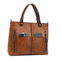 Sac à main en cuir marron avec poches avant zippées, contenant un smartphone et des cartes. Élégant et pratique pour un usage quotidien.