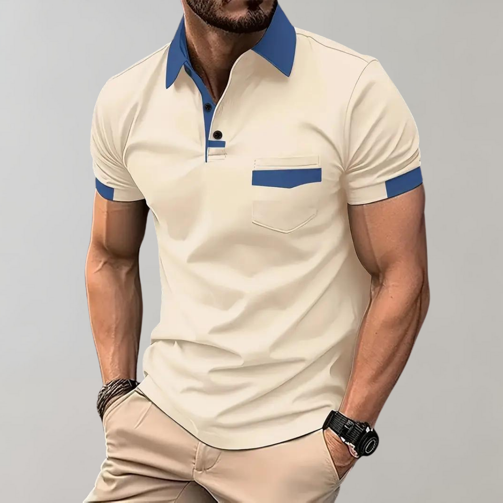 Homme portant un polo beige à col bleu, manches courtes, poche poitrine, assorti à un pantalon beige. Mode masculine élégante et décontractée.