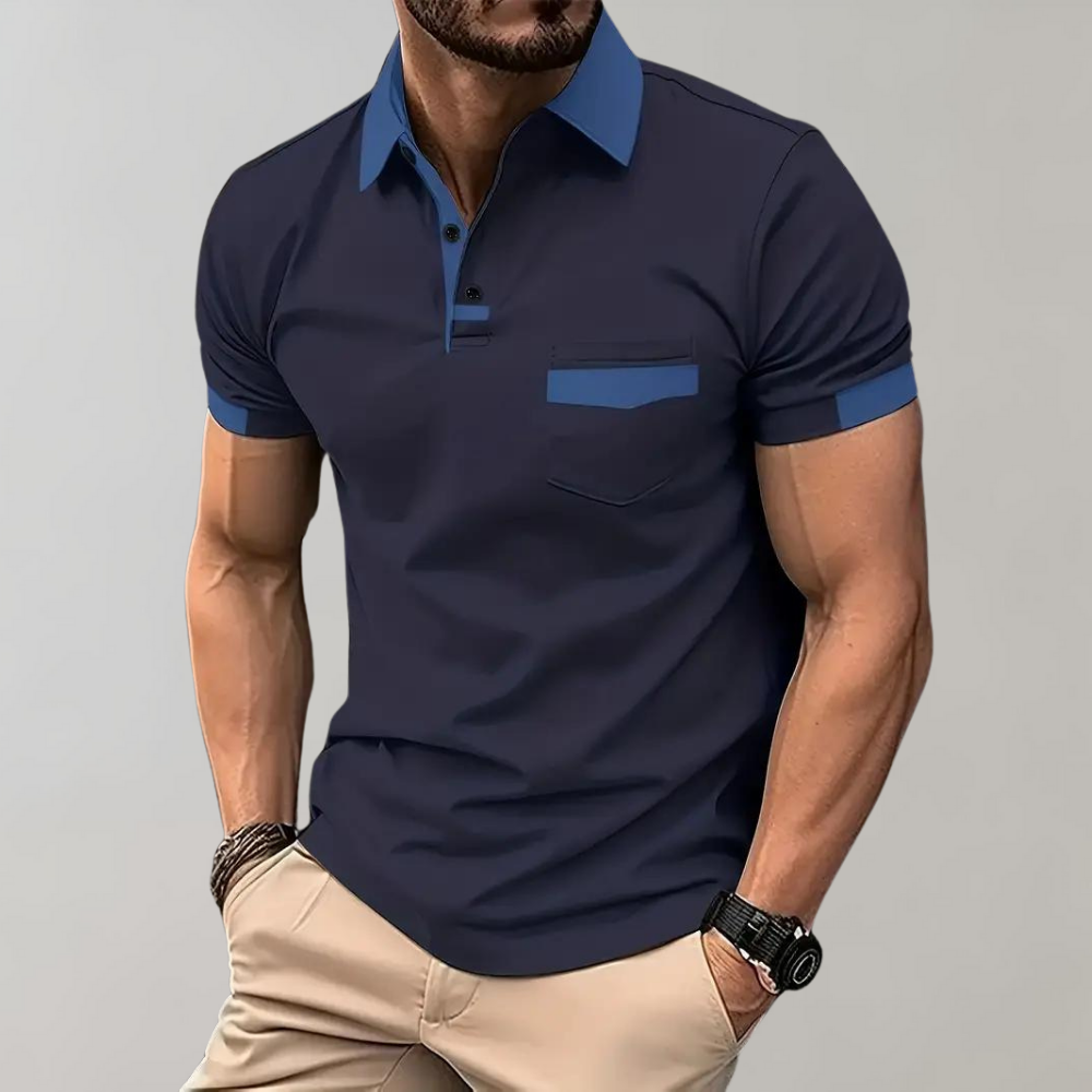 Homme portant un polo bleu marine élégant avec col contrastant, manches courtes, poche poitrine, associé à un pantalon beige. Mode masculine chic.