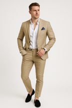 Homme en costume beige élégant, chemise blanche, pochette bleue, posant debout. Mode masculine, tenue formelle, style chic et moderne.