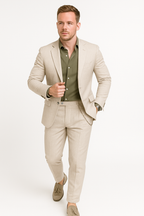 Homme en costume beige élégant, chemise verte, marchant, montre-bracelet visible. Mode masculine, style chic, tenue professionnelle.