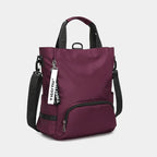 Sac à dos Tigernu violet avec bandoulières noires, poche avant zippée et étiquette de marque. Design moderne et fonctionnel pour usage quotidien.