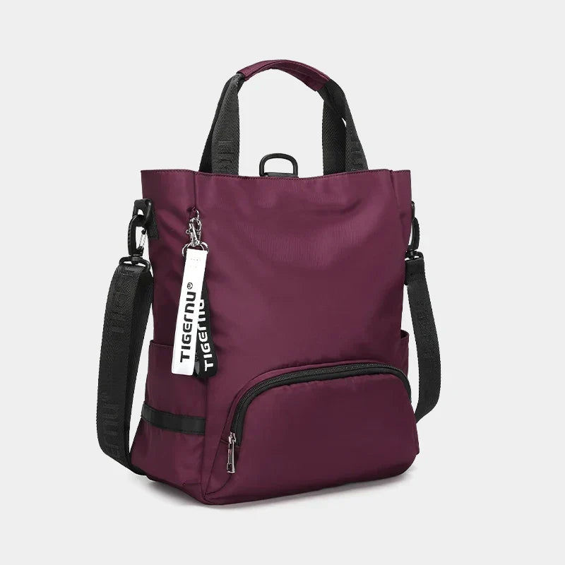 Sac à dos Tigernu violet avec bandoulières noires, poche avant zippée et étiquette de marque. Design moderne et fonctionnel pour usage quotidien.