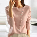 Femme portant un pull rose en cachemire avec boutons, manches longues, col rond, style élégant et décontracté, mode automne-hiver.
