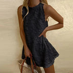 Robe noire sans manches avec motifs floraux, femme tenant un sac en osier. Mode estivale élégante, tenue décontractée chic.