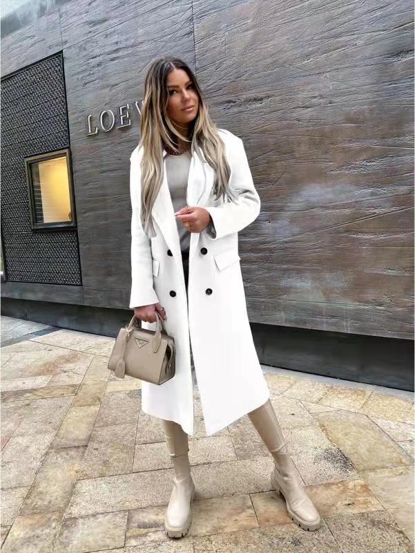 Femme en manteau blanc élégant, tenant un sac à main beige devant un mur texturé. Mode automne chic, style urbain moderne.