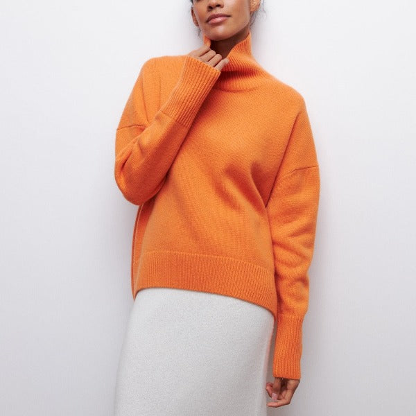 Femme portant un pull orange à col roulé, manches longues, sur une jupe blanche. Mode automne, style décontracté, tendance vêtements chauds.