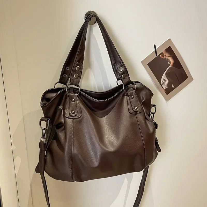 Sac à main en cuir marron suspendu à un crochet, avec une photo accrochée à côté. Mode, accessoires, sac à main élégant, tendance.