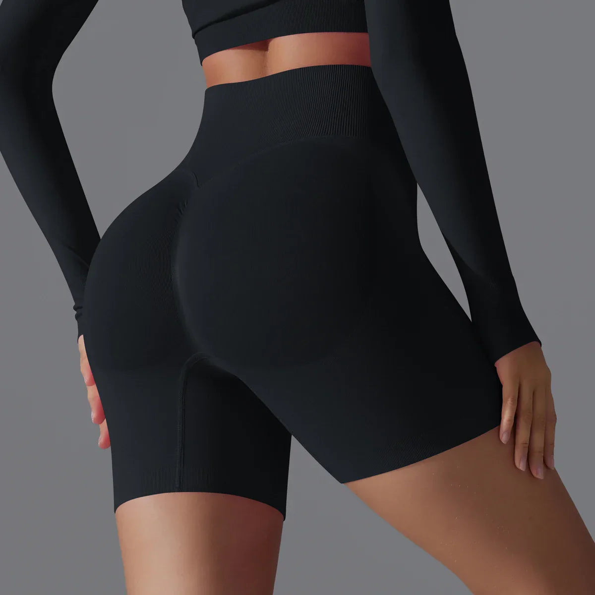 Femme portant un short de sport noir taille haute, mettant en valeur la silhouette. Vêtements de fitness, mode active, confort et style.