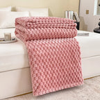 Couverture en peluche rose texturée sur un lit blanc, chambre moderne, décoration intérieure élégante, confort et style, ambiance cosy.