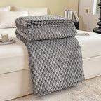 Couverture en fausse fourrure grise texturée sur un lit blanc, chambre moderne, décoration intérieure élégante, confort et style.