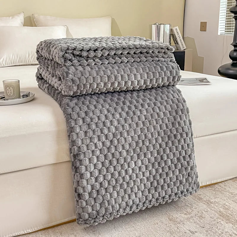 Couverture en fausse fourrure grise texturée sur un lit blanc, chambre moderne, décoration intérieure élégante, confort et style.