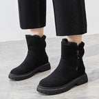 Bottes noires en daim pour femme avec semelles épaisses, fermetures éclair latérales, portées avec un pantalon noir. Mode hiver élégante et confortable.