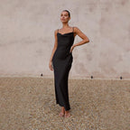 Robe longue noire élégante portée par une femme, posant sur un fond neutre. Mode féminine chic, tenue de soirée sophistiquée.