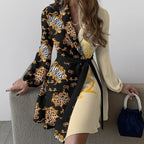 Robe asymétrique élégante avec motifs animaliers, manches longues, ceinture noire, tenue chic pour femme, sac à main bleu, style moderne et tendance.
