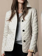 Veste matelassée beige pour femme, élégante et moderne, avec boutons noirs, col relevé, manches longues, idéale pour mode automne-hiver.