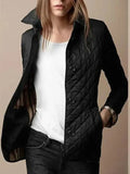 Femme portant une veste matelassée noire élégante, col relevé, sur un t-shirt blanc, style décontracté chic, mode automne-hiver tendance.