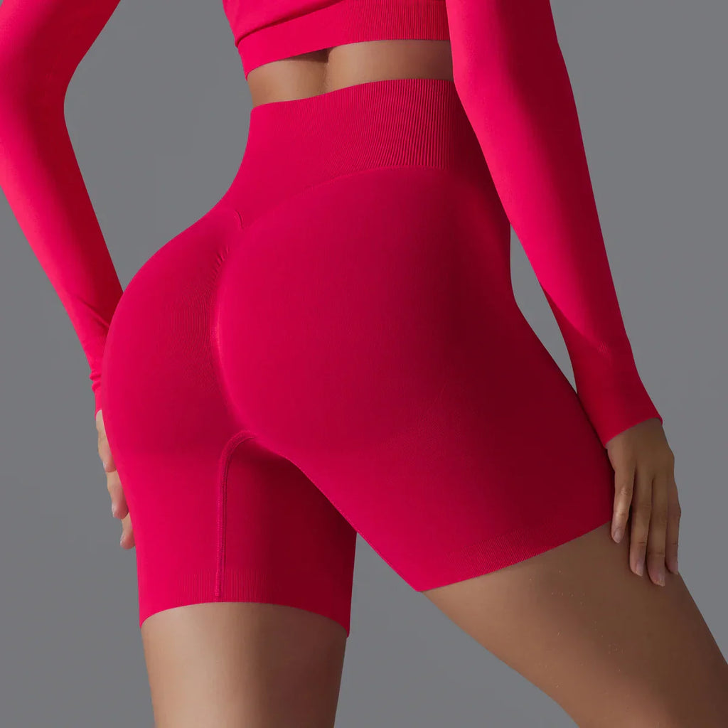 Femme portant un short de sport moulant rose vif, taille haute, mettant en valeur la silhouette. Mode fitness, vêtements de sport tendance.
