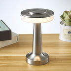 Lampe de table moderne en métal argenté sur bureau en bois, avec livres et plante succulente en arrière-plan. Éclairage LED élégant et contemporain.