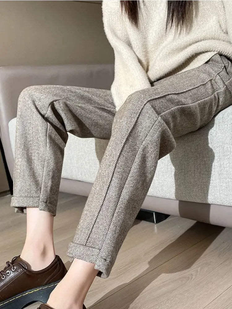 Pantalon en laine grise à chevrons, coupe droite, porté avec un pull beige et des chaussures marron, style automne-hiver élégant et décontracté.