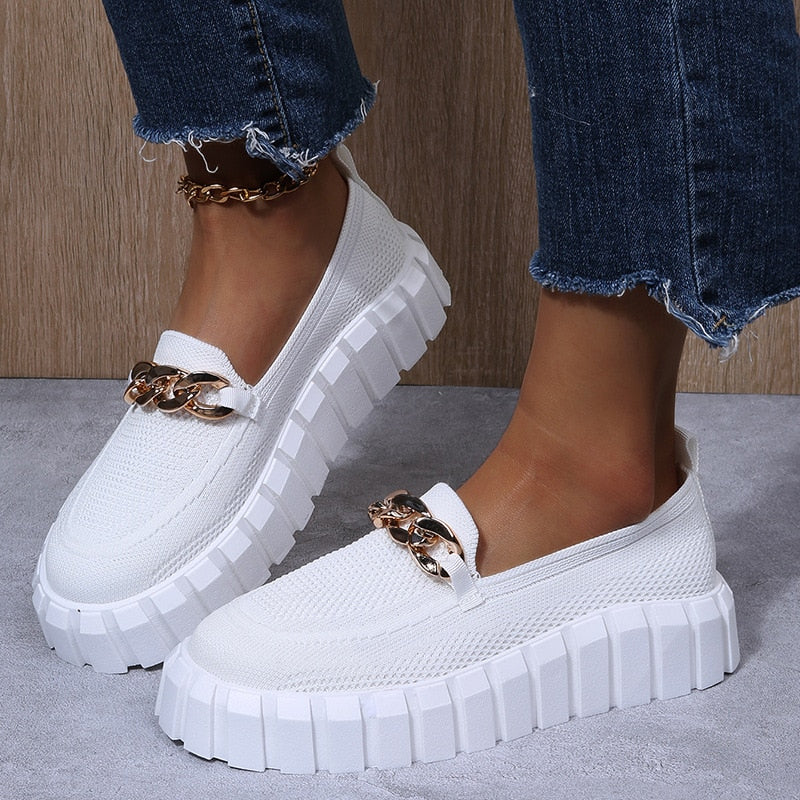 Chaussures blanches tendance avec semelle épaisse et chaîne dorée, portées avec un jean décontracté. Mode féminine, style urbain, chaussures modernes.