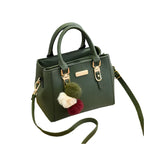 Sac à main vert en cuir avec bandoulière, orné de pompons colorés. Élégant et moderne, idéal pour la mode féminine et les accessoires tendance.