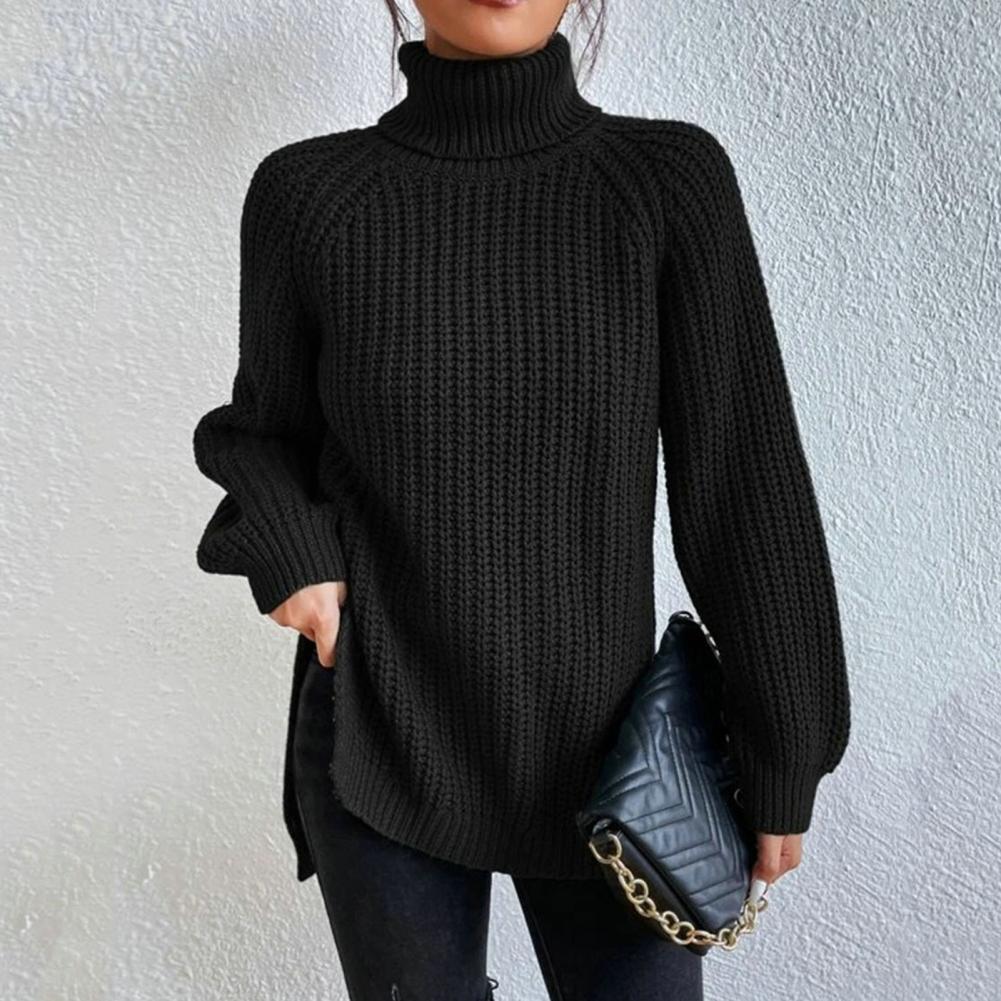 Pull noir à col roulé en maille épaisse, porté avec un sac à main matelassé noir à chaîne dorée, sur fond de mur texturé blanc.