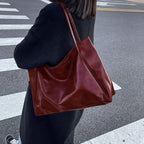 Sac à main en cuir marron porté par une personne en manteau noir, sur un passage piéton. Accessoire mode élégant et tendance pour femme.