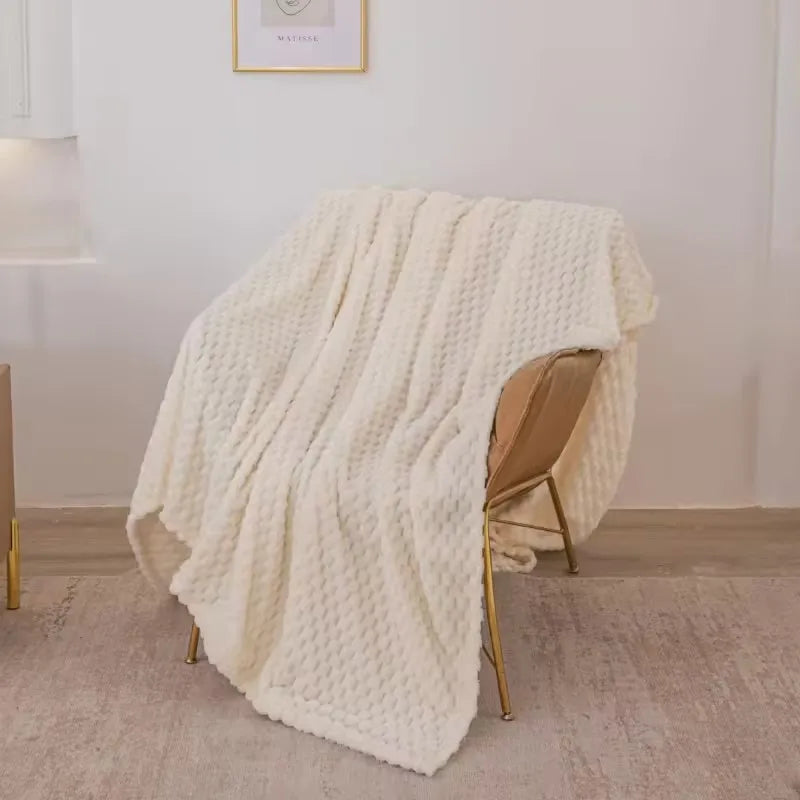 Plaid en laine blanche texturée drapé sur un fauteuil moderne en cuir beige, intérieur minimaliste, décoration cosy et élégante.